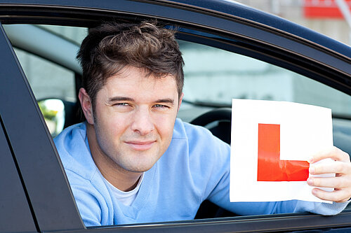 Person sat in a car holding up an L-plate